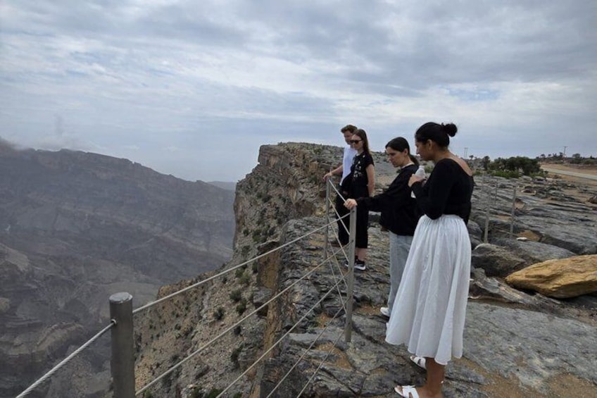 A group of people standing on a rocky outcrop with a canyon in the background. 3