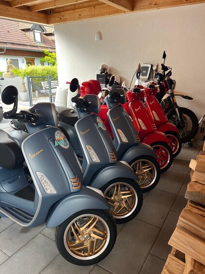 A row of scooters parked indoors, with a wooden ceiling and a white wall in the background. 3
