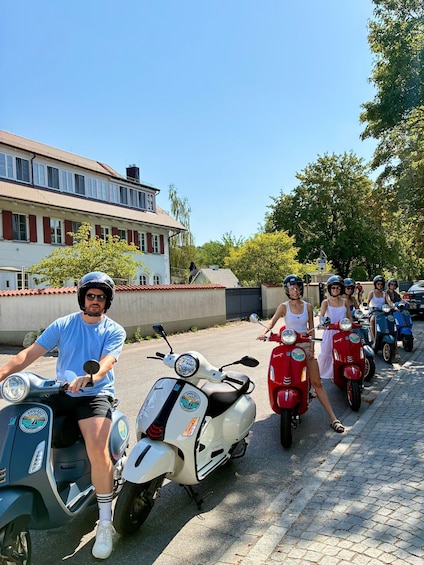 A group of people on scooters, a building, and trees. 5