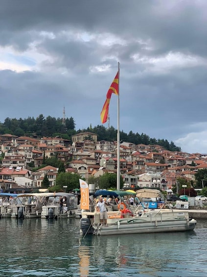 A coastal town with a flagpole, boats, and a densely packed hillside in the background. 4