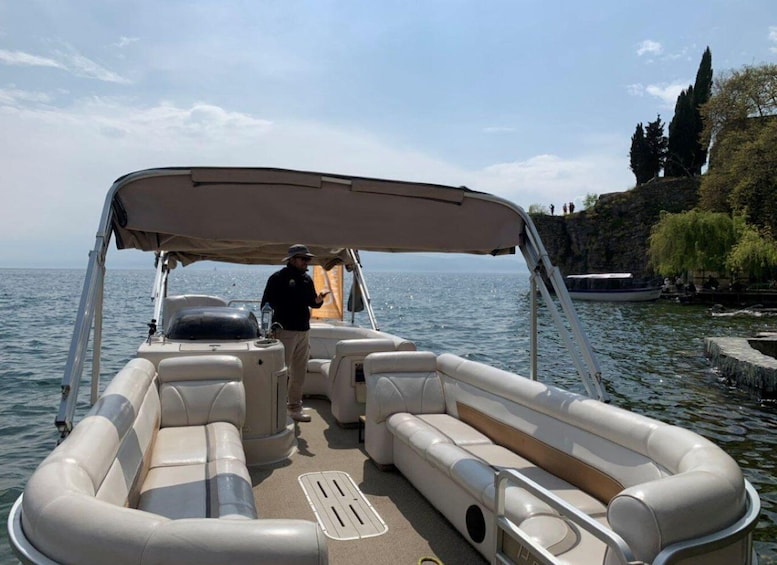 A motorboat with a canopy, equipped with seating and a steering wheel, on a calm body of water. 1