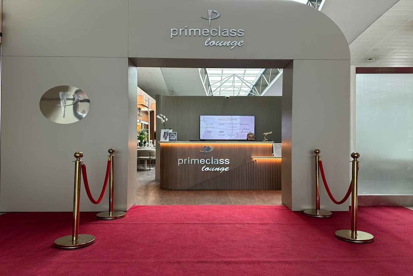 A red carpet entrance to a lounge with a reception desk and a 'Welcome' sign. 5