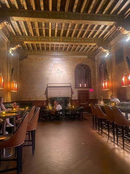 An interior with wooden beams, a fireplace, and tables with chairs. 3
