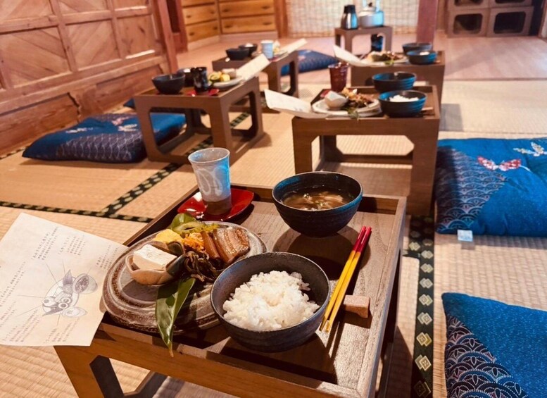 A traditional Japanese meal setup with a wooden table, a bowl of soup, a plate of rice, and various dishes. 3