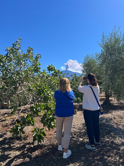 Two people taking a photo of a volcano in the background. 2
