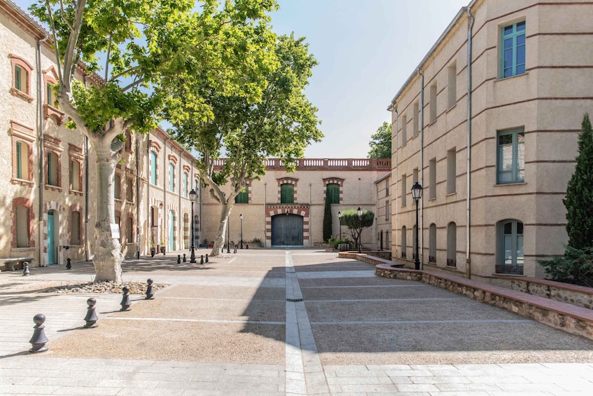 A courtyard with buildings, trees, and a central gate. 1