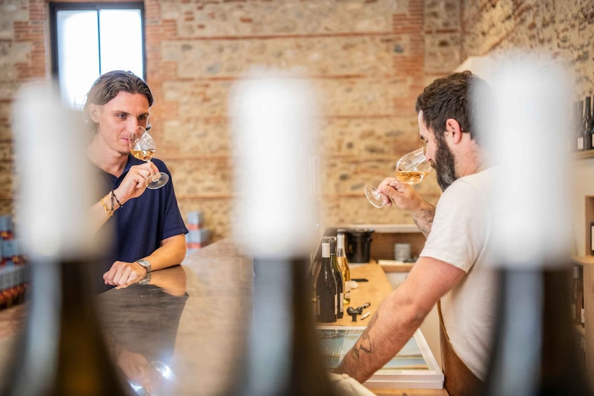 Two people tasting wine in a rustic cellar with wooden walls and a counter. 2
