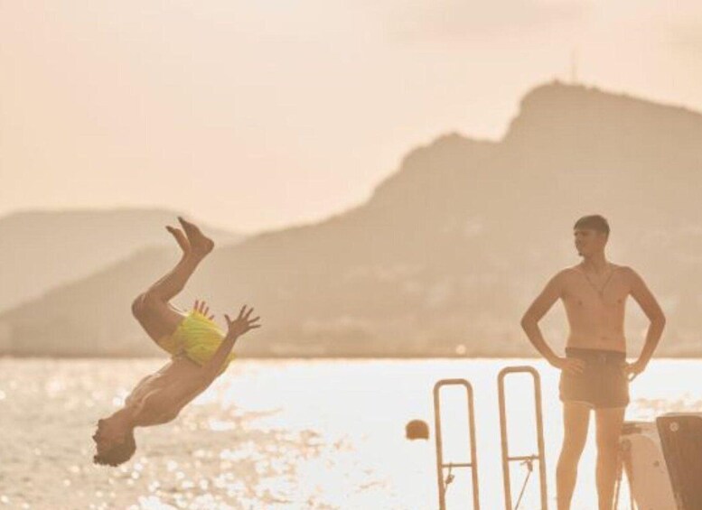 A person diving into the water with a mountain in the background. 2