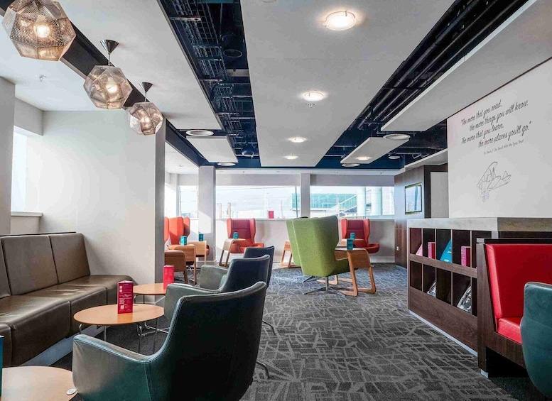A modern reading area with leather couches, colorful chairs, and a patterned carpet. 1