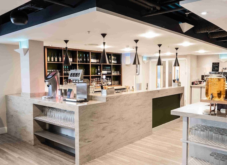 A modern bar with a marble counter, pendant lighting, and shelves stocked with bottles. 2
