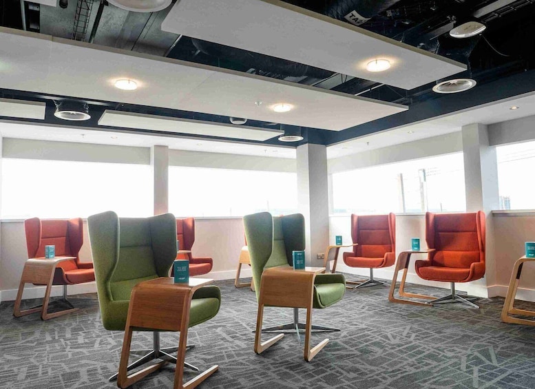 A waiting area with multiple chairs and tables, large windows, and a ceiling with recessed lighting. 3