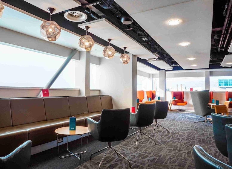 A modern interior with a brown leather bench, black chairs, and patterned carpet. 5