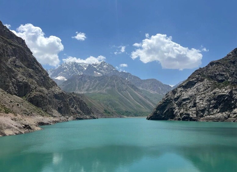 A turquoise lake surrounded by rugged mountains under a clear sky. 4