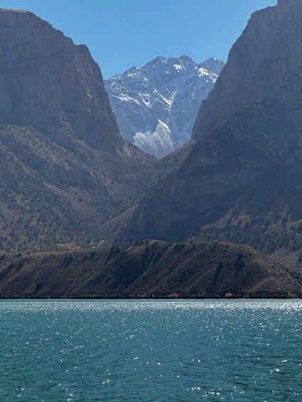A mountainous landscape with a body of water in the foreground and snow-capped mountains in the background. 2