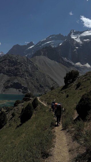 A group of hikers on a mountain trail with snow-capped peaks in the background. 3