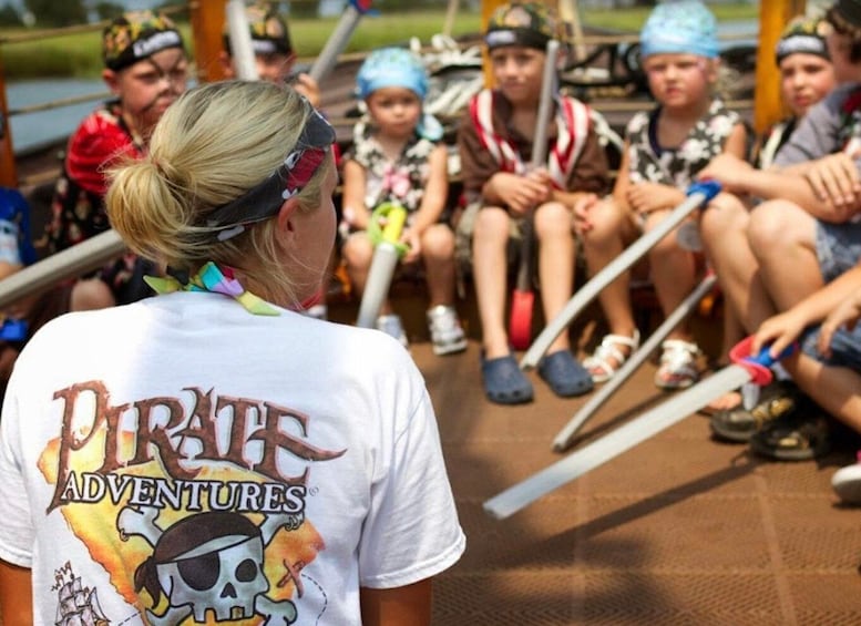 A group of people sitting on a wooden deck outdoors, some wearing hats and bandanas. 4