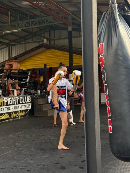 A person practicing martial arts, wearing a white and blue uniform, with a punching bag in the foreground. 2