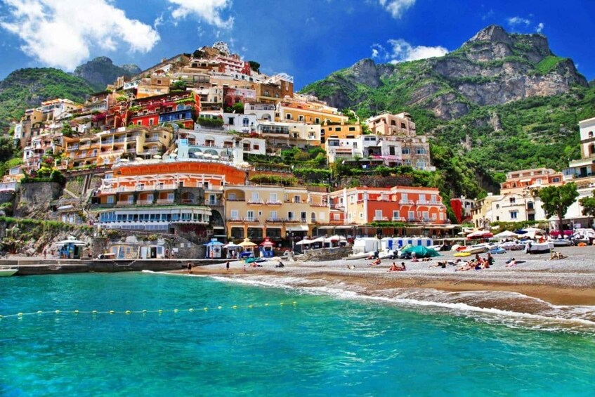 A coastal town with colorful buildings, a beach, and mountains in the background. 4