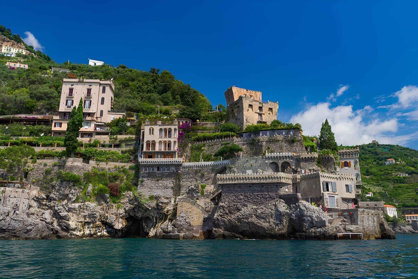 A coastal town with historic stone buildings, a castle, and lush greenery. 3