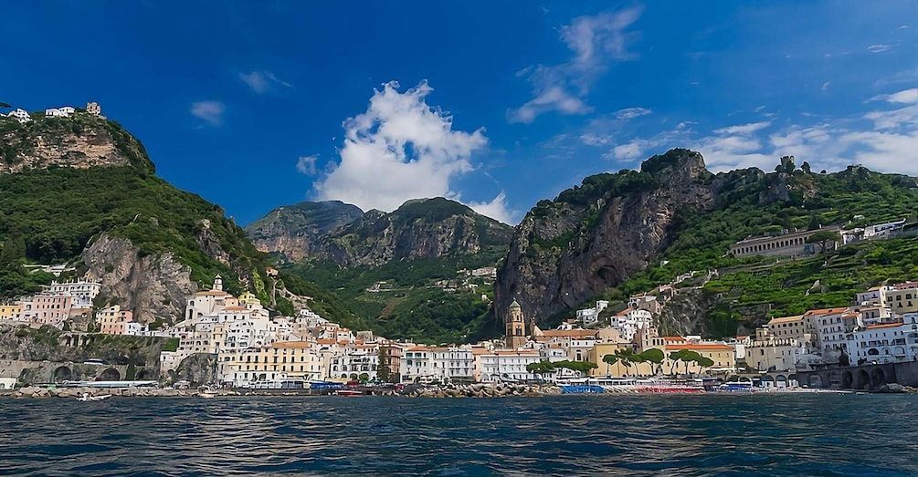 A coastal town with buildings on steep hills, a clear blue sky, and calm sea. 5