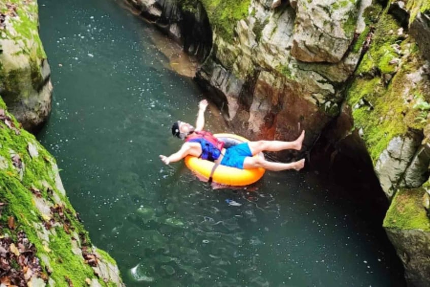 A person floating on an inflatable tube in a narrow water channel surrounded by rocky cliffs. 2