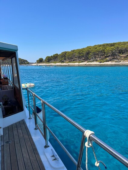 A boat on a clear blue sea with a sandy beach and green trees in the background. 3
