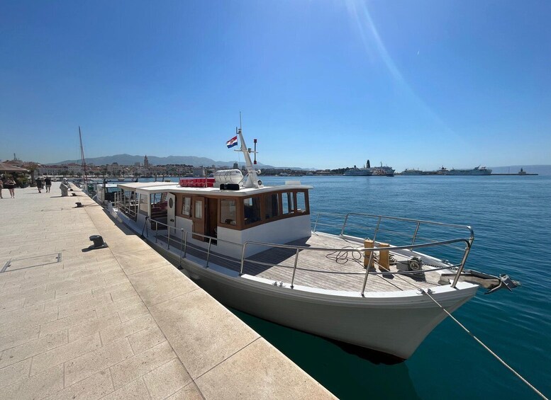 A boat docked at a pier with a clear sky and calm water. 1