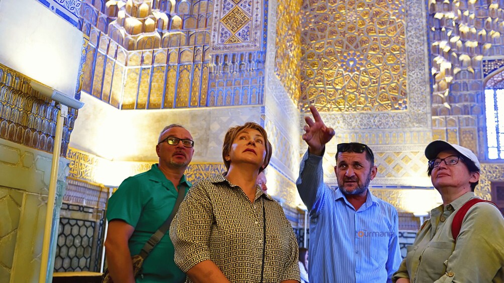 A group of people inside a building with ornate golden and blue patterned ceilings and walls. 4