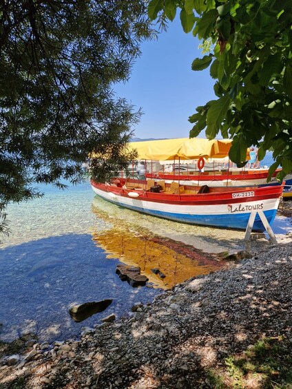 A colorful boat docked at a rocky shore with clear water. 4