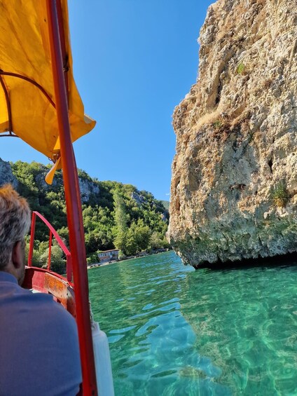 A boat with a red canopy, clear turquoise water, and rocky cliffs. 2