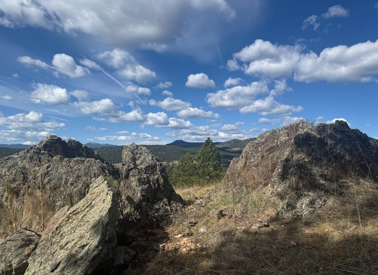 A mountainous landscape with rocky outcrops and a clear blue sky with scattered clouds. 5
