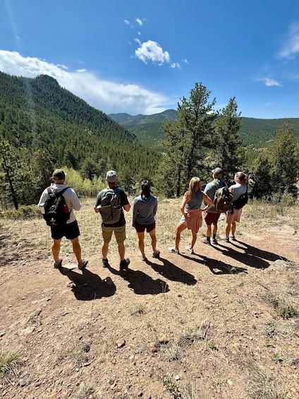 A group of hikers on a dirt trail with a mountainous landscape in the background. 3