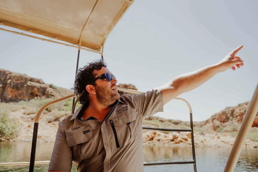 A person pointing towards the water on a boat. 5