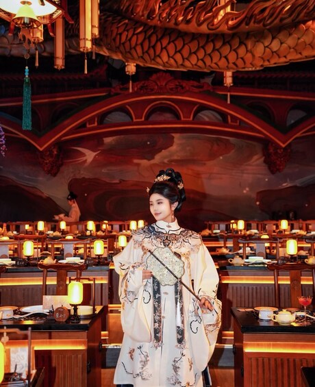A person in traditional attire standing in a room with ornate decorations and tables set for a meal. 3