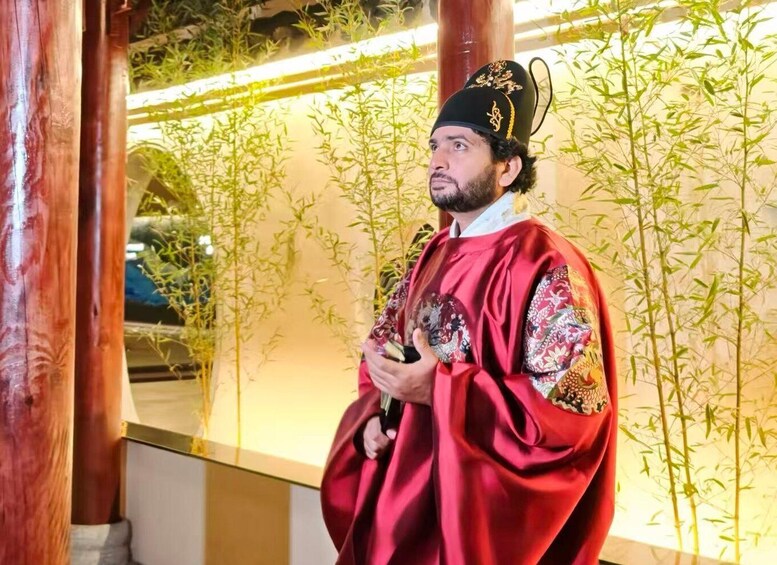 A person in traditional attire standing in front of a bamboo plant. 5