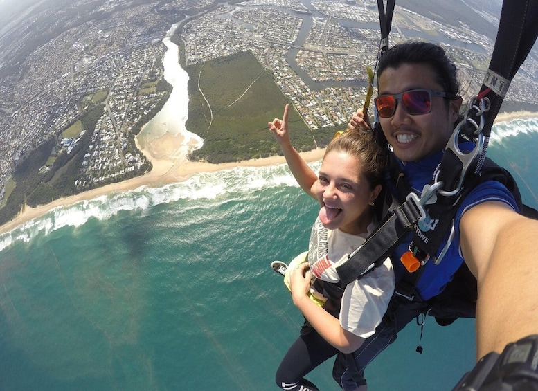 A person skydiving with a child, overlooking a coastal city and beach. 5