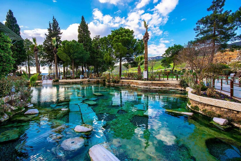 A clear water body with rocks, surrounded by trees and a stone wall. 2