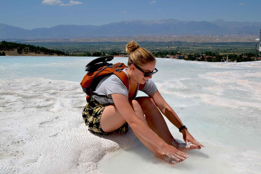 A person sitting on a salt flat with a mountainous landscape in the background. 3
