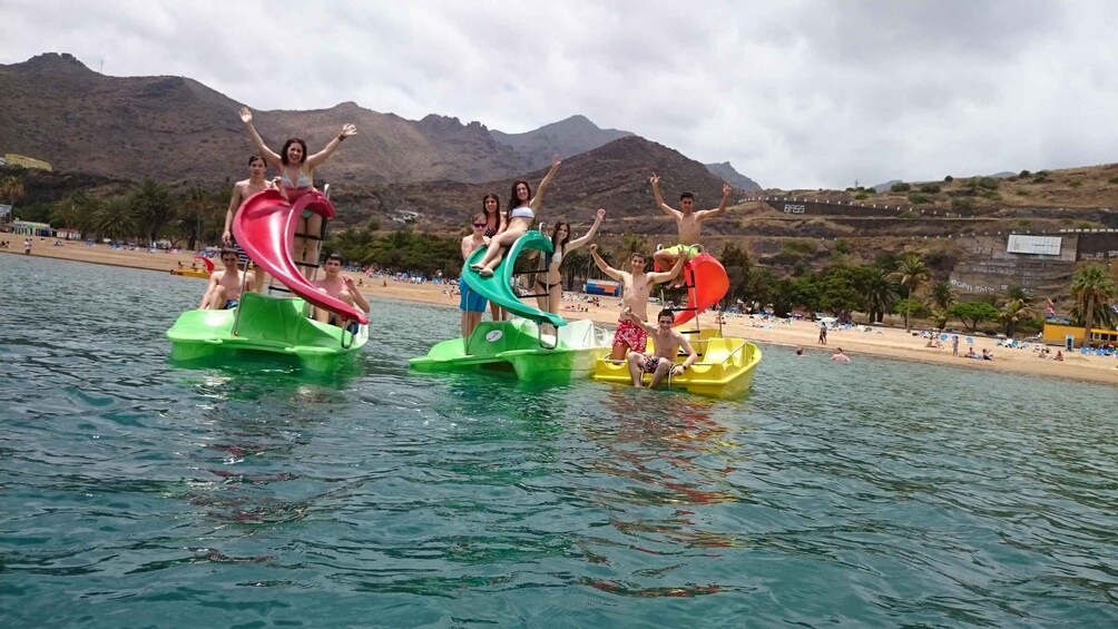 People on watercrafts with a beach and mountains in the background. 2