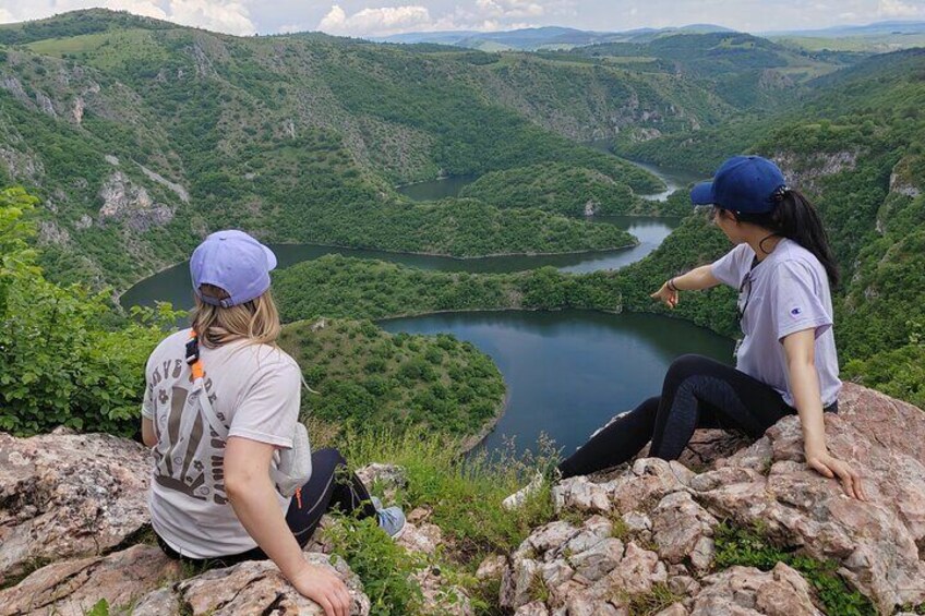 Two people sitting on a rocky outcrop overlooking a river valley. 2