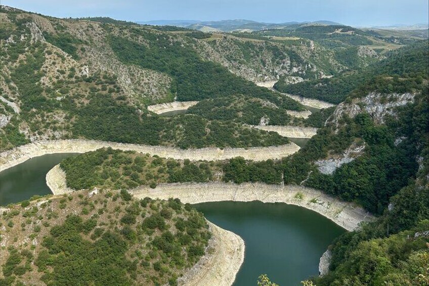 A river winding through a mountainous landscape with dense green vegetation. 1