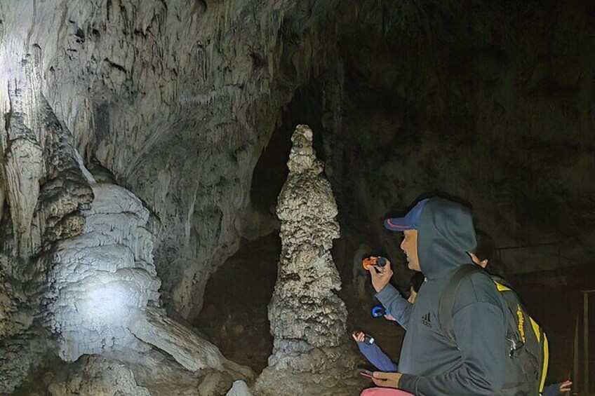 A cave with stalactites and stalagmites, and two people examining a rock formation. 5