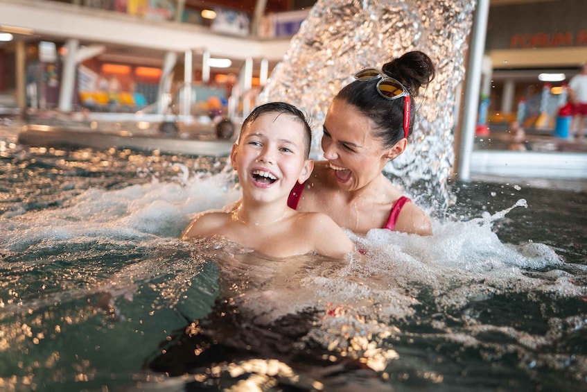 Two people in a water play area with water splashing around them. 4