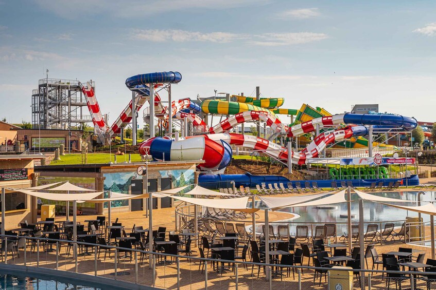 A water park with various water slides and a pool area with lounge chairs and tables. 1