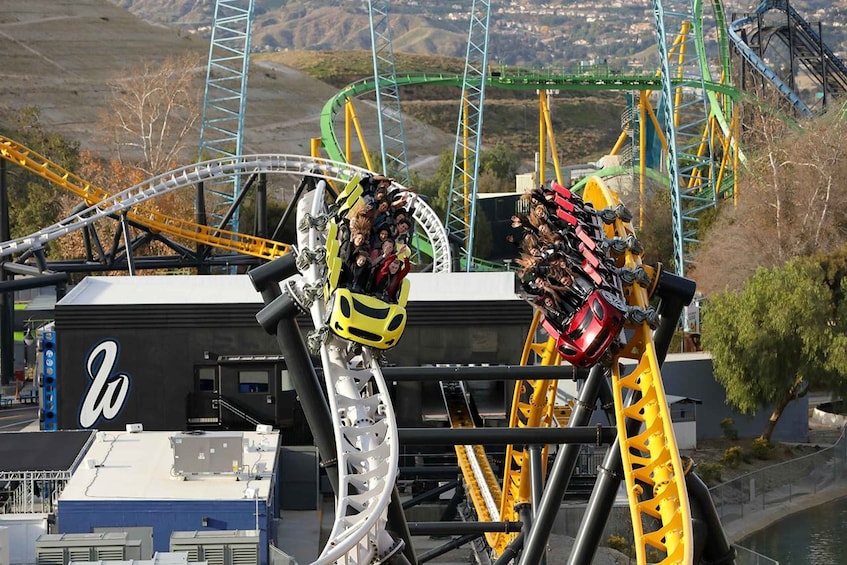 A roller coaster with a steep drop and a loop, surrounded by a mountainous landscape. 3