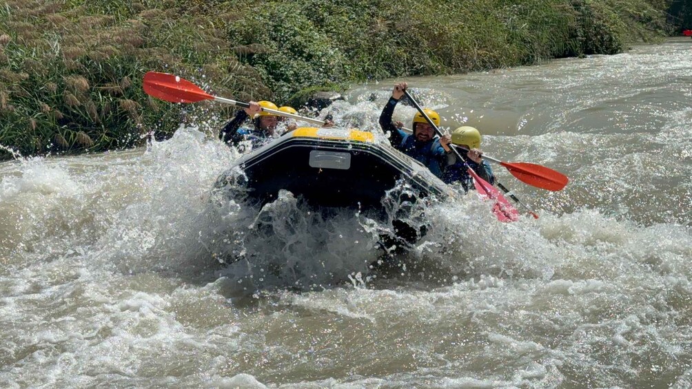 A group of people in a raft navigating through a river with white water. 2