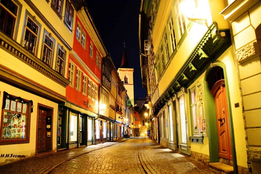 A cobblestone street lined with colorful buildings at night. 2