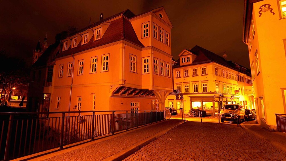 A nighttime street scene with buildings illuminated by warm lighting. 4