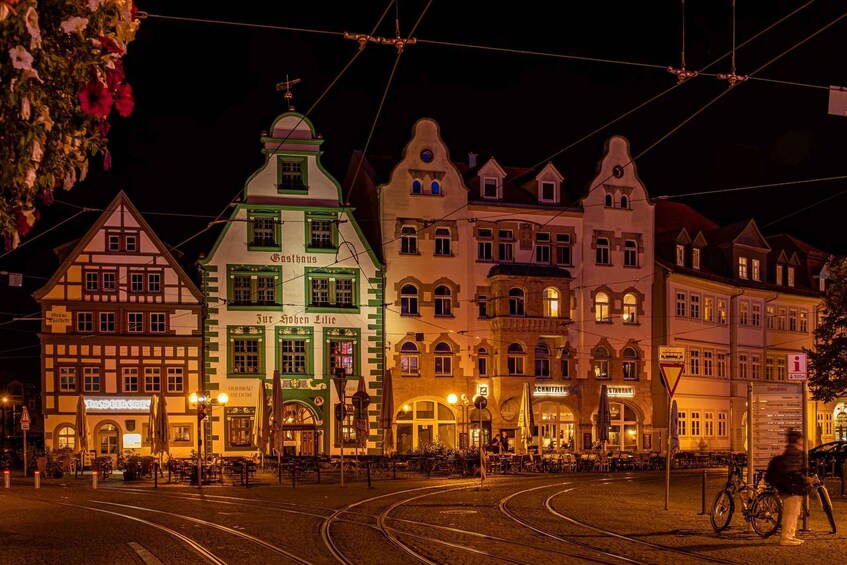 A nighttime street scene with tram tracks, traditional European buildings, and a tram. 1