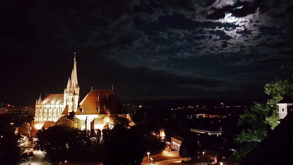 A church with a tall spire and a moon in the sky. 5